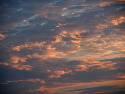 [Small spots of blue dot this image as the sun lights the right-most edges of the cloud sections. These clouds are very irregular in shape so lots of distinct color changes within the image ranging from light-blue to dark blue and pinkish-white.]